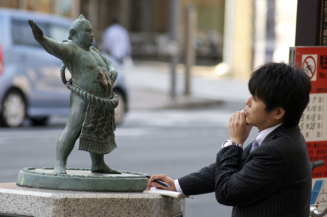 Das Praktische zählt: Ein Salaryman vor einer Statue eines Sumo-Ringers.