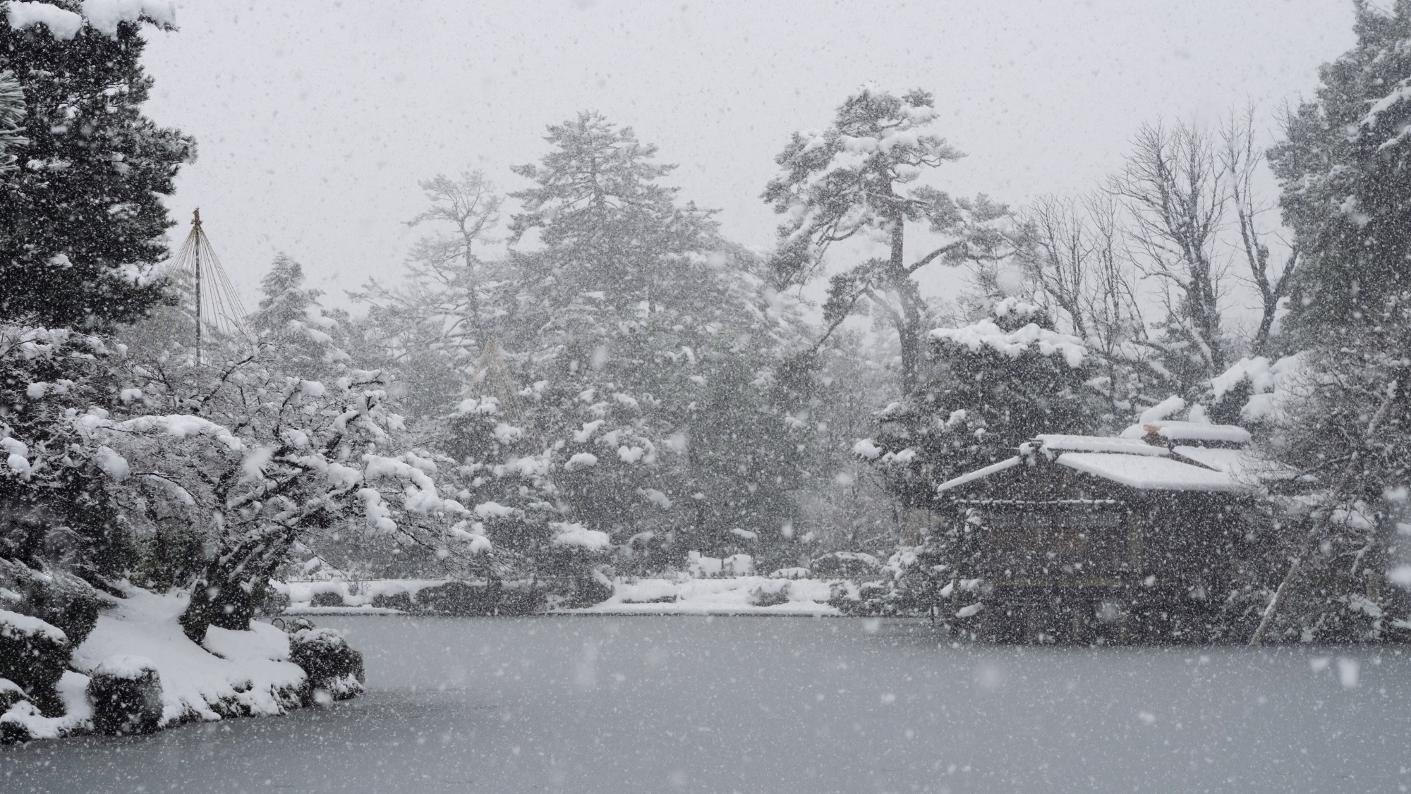 Der Kenrokuen mit dem Teehaus und dem Teich an einem Schneetag.