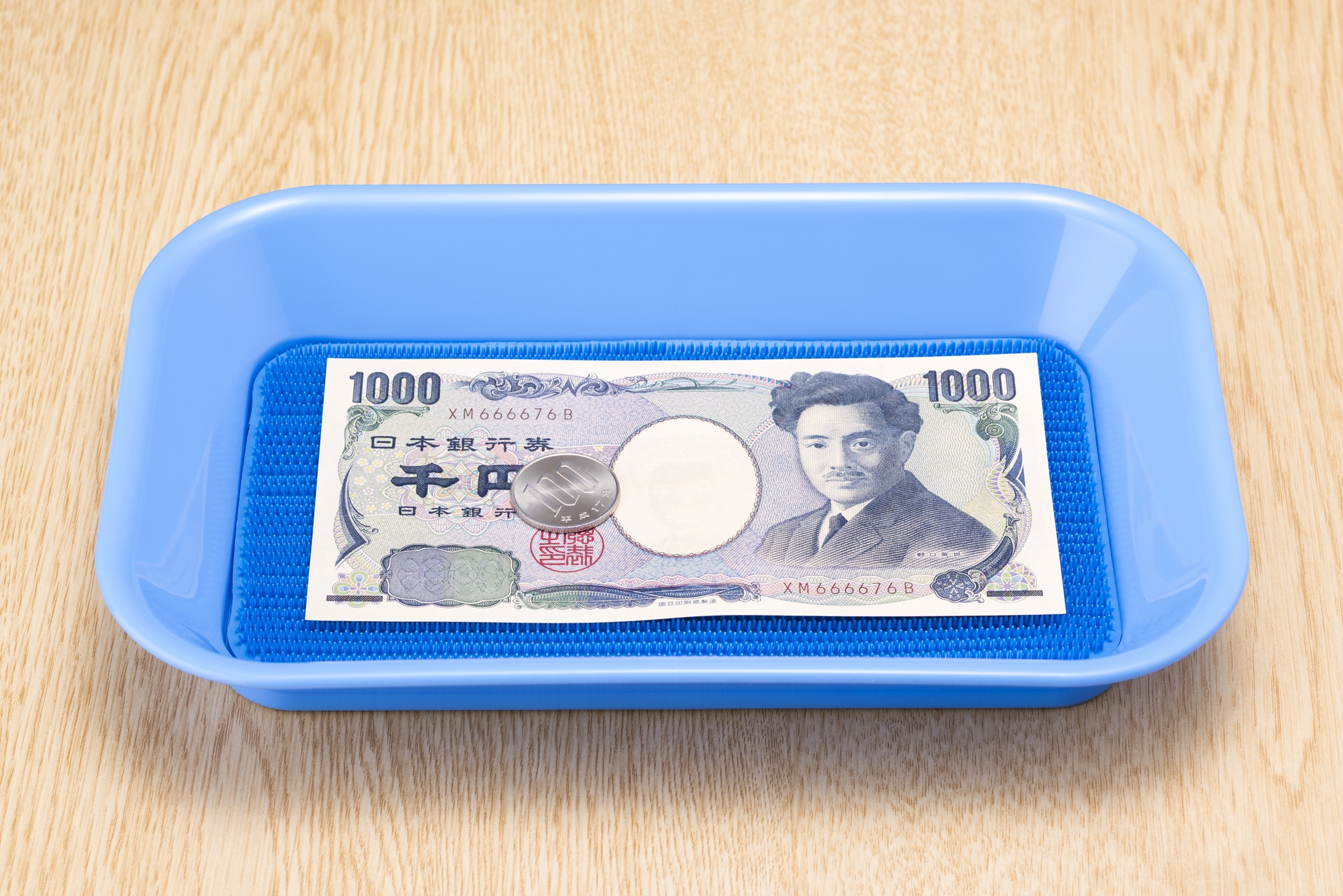 Eine Zahlschale mit einer 1000-Yen-Note und einer Münze im Wert von 100 Yen.